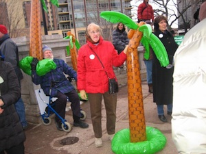 Protesters carry inflated palm trees, mocking footage from Fox News of a "Wisconsin" rally highlighting angry pro-union protesters with palm trees in the background